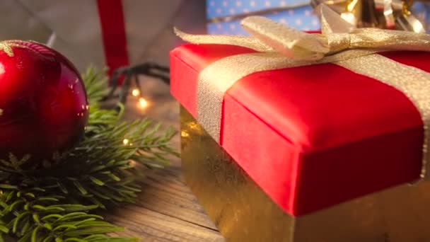 Closeup 4k video of camera flying over Christmas gifts from santa, glowing light garlands and colorful baubles — Stock Video