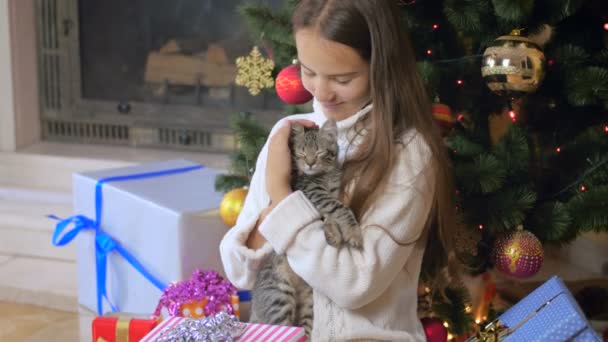 Güzel genç kız sevişme şirin yavru kedi Noel ağacının altında 4 k video — Stok video