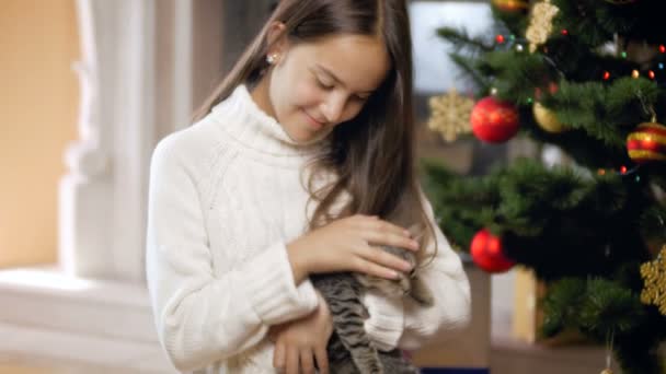 4 k video Roztomilý kotě a dospívající dívka hraje pod vánoční stromeček doma — Stock video