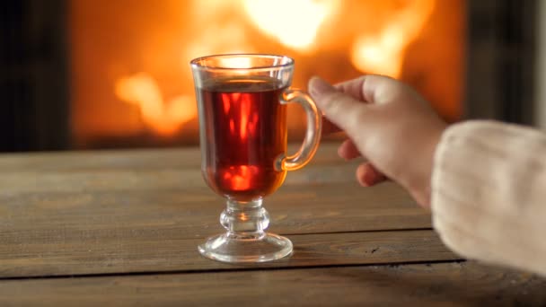 Крупный план 4k кадры молодой женщины в свитере, пьющей горячий чай у горящего камина — стоковое видео