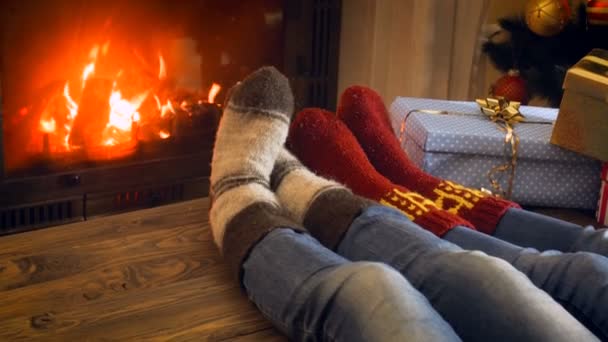 4k video de la familia en calcetines de lana de punto descansando junto al árbol de Navidad en la chimenea en llamas — Vídeo de stock