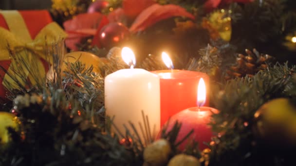 Крупним планом 4k відео трьох палаючих свічок в різдвяний вінок вночі — стокове відео