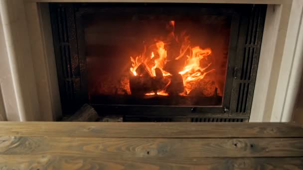 Filmagem em câmera lenta de fogo queimando na lareira na sala de estar com mesa de madeira — Vídeo de Stock