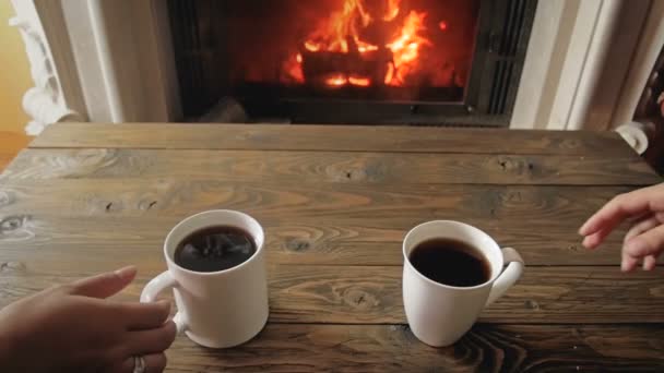 Imágenes en cámara lenta de una pareja tomando té de tazas junto a la chimenea en la sala de estar — Vídeo de stock