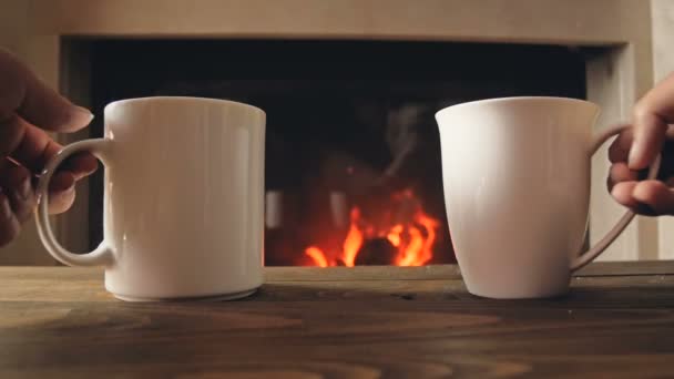 Крупный план замедленной съемки пары, сидящей у камина и принимающей чашки чая — стоковое видео