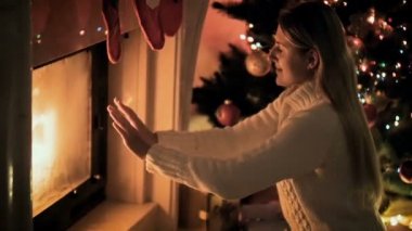 Noel arifesinde şömine yanıyor ısınma gülümseyen genç kadın slow motion video