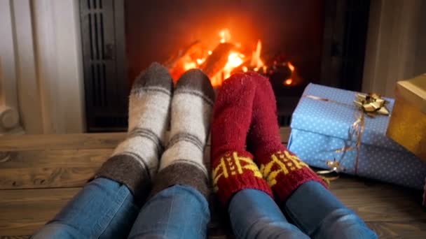 Filmagem em câmera lenta de duas pessoas usando meias de lã de malha descansando junto à lareira em casa — Vídeo de Stock