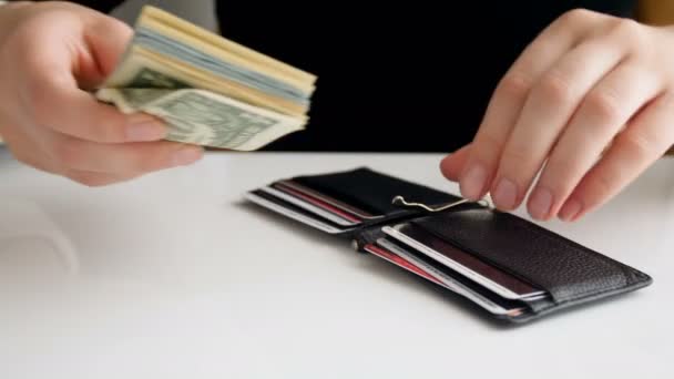Запись крупным планом, на которой деловая женщина кладет пачку долларов и пытается закрыть бумажник. — стоковое видео