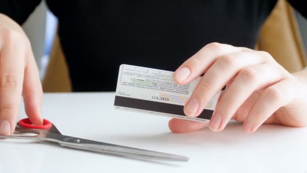 Крупним планом 4k кадри молодої жінки, що ріжуть кредитну картку з ножицями. Проблеми з банком та банкрутством — стокове відео