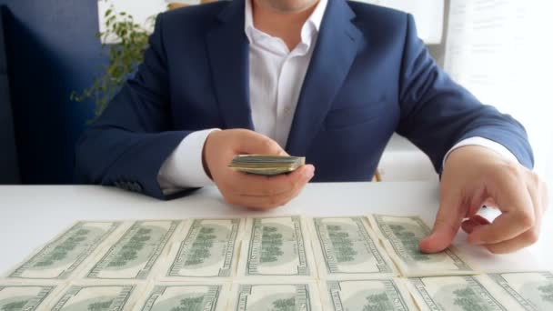 Imágenes de 4k del exitoso empresario colocando y contando una gran pila de dólares estadounidenses en el escritorio de la oficina — Vídeo de stock