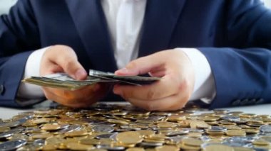 Açgözlü işadamı kavramı. Para dolu masa başında oturan ve büyük yığını banknot sayma elbiseli Genç adam