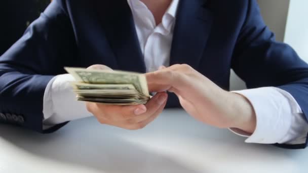 Imágenes en cámara lenta del exitoso hombre de negocios lanzando dinero desde una gran pila de dólares — Vídeo de stock