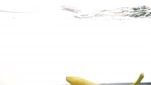 Närbild 4k film av färsk mogen banan faller i vattnet — Stockvideo