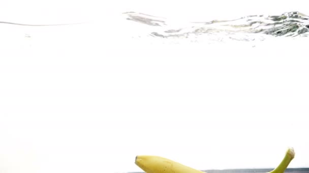 Images 4k de bananes fraîches mûres tombant dans l'eau 