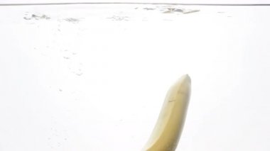 Düşen ve beyaz arka plan etrafında su sıçramasına muz closeup ağır çekim görüntüleri