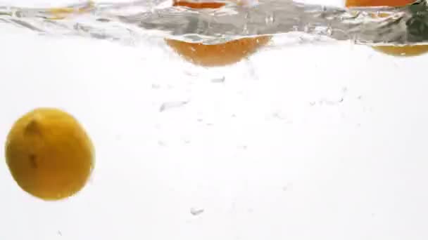 Closeup 4k beelden van drie sinaasappels vallen in water tegen witte backgorund — Stockvideo