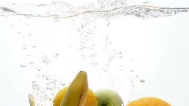Closeup ağır çekim video düşen ve beyaz arka plan karşı su sıçramasına taze ve olgun tropikal meyveler