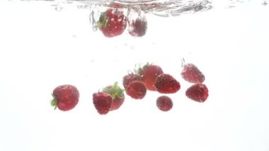 Taze olgun çilek ve ahududu yavaş yavaş düşüyor ve temiz su sıçramasına closeup video