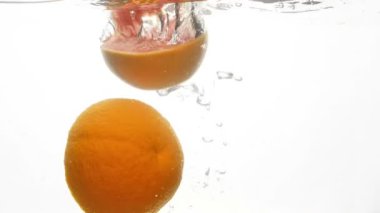 Limon, portakal ve greyfurt düşen ve beyaz arka plan karşı soğuk açık suda sıçraması yarısı kesilmiş slow motion video