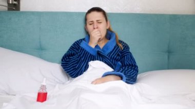 yatakta yatan ve boğaz sprey kullanarak genç hasta kadın 4 k video