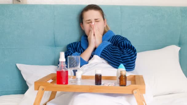 4k vídeo de jovem doente deitado na cama, soprando o nariz e usando spray nasal — Vídeo de Stock