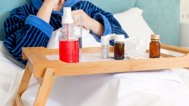 Nahaufnahme 4k Filmmaterial einer kranken Frau im Bademantel, die Tabletten, Sprays und Medikamente aus Tabletts nimmt — Stockvideo