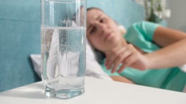 4 k closeup video genç kadının başından acı acı çekiyorum yatakta yatan ve aspirin bardakta içki