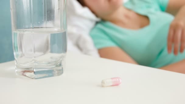 4 k βίντεο closeup της νεαρής γυναίκας που πάσχουν από τον πόνο, ξαπλωμένη στο κρεβάτι και πίνοντας χάπι — Αρχείο Βίντεο