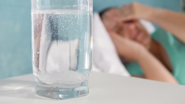 Primer plano 4k metraje de la píldora de aspirina disolver y burbujear en un vaso de agua — Vídeo de stock