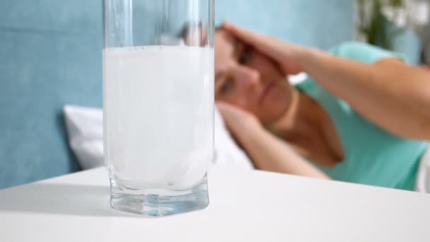Primo piano video al rallentatore della compressa di aspirina che si scioglie in un bicchiere d'acqua sul comodino — Video Stock