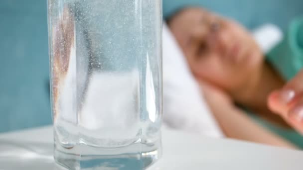 特写慢镜头的妇女头痛躺在床上, 拿着玻璃杯水阿司匹林和喝它 — 图库视频影像