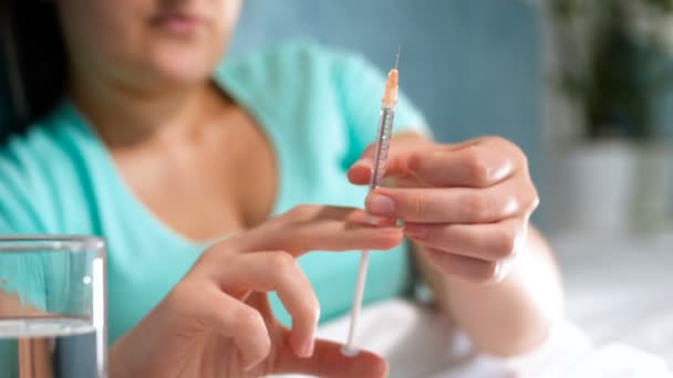 Primer plano video en cámara lenta de una mujer enferma acostada en la cama y preparando la jeringa para inyección. Golpear con el dedo para liberar burbujas de aire . — Vídeos de Stock