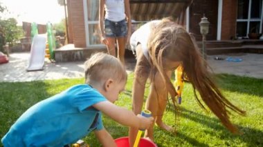 iki ablası Oyuncak silahtan su ile çekim mutlu gülen yürümeye başlayan çocuk 4 k görüntüleri