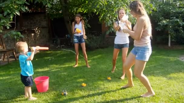 4k Filmmaterial von glücklicher aktiver Familie, die mit Wasserpistolen auf Gras im Hinterhof spielt — Stockvideo