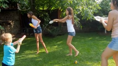 su savaşı arka bahçe sahip mutlu etkin aile 4 k video. İnsanların sıçramasına ve su üst üste sıcak güneşli gün dökme