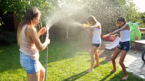 Vidéo 4k de rire heureux famille jouer avec tuyau d'arrosage et pistolets à eau à la maison arrière-cour — Video