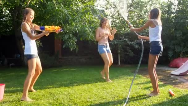 Vidéo 4k de la famille heureuse jouant avec arrosage tuyau d'arrosage et pistolets jouet d'eau sur l'herbe à l'arrière-cour par une chaude journée ensoleillée — Video