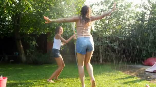 4 k film av lycklig ung familj avkopplande och kylning under vatten besprutning från trädgårdsslang på bakgården — Stockvideo