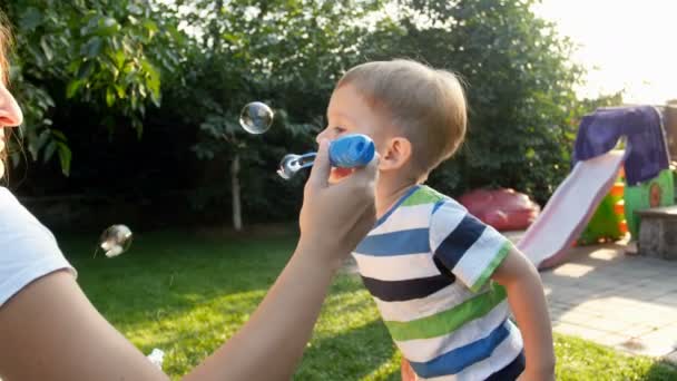 4k Filmmaterial von kleinen Kleinkind Junge pustet Seifenblasen mit Familie auf Gras im Hinterhof — Stockvideo