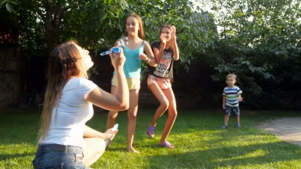 4k filmato di allegri bambini felici che saltano in alto e catturano bolle di sapone volante — Video Stock