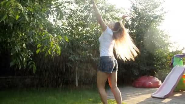 4 k film av glad ung kvinna njuter av regn på varm sommardag på bakgården — Stockvideo