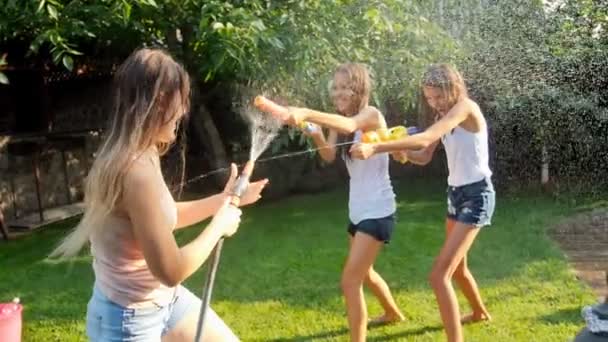 Video al rallentatore di due ragazze che ridono avendo battaglia pistola ad acqua con la madre sull'erba in cortile — Video Stock