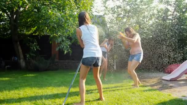 Vídeo en cámara lenta de la familia alegre salpicando agua entre sí de manguera de jardín y pistolas de juguete — Vídeo de stock