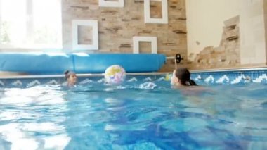 4 k video, iki genç kız kapalı yüzme havuzunda renkli plaj topu ile oynarken