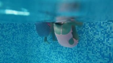 Yüzme havuzunda eğleniyor ve salto ve takla mayo'de iki kız 4 k video