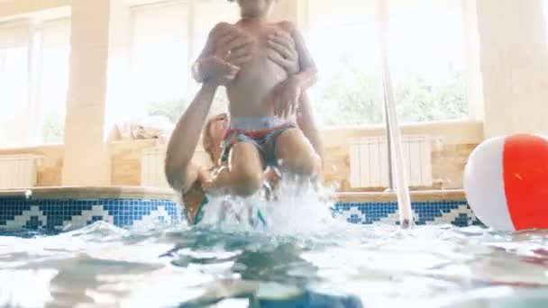 4 k-video av glad skrattande småbarn pojke simma med ung mamma på inomhuspool — Stockvideo