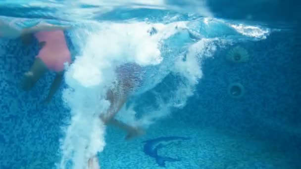 Подводная 4k-съемка двух девочек-подростков, прыгающих и ныряющих в бассейне — стоковое видео