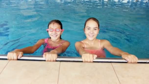 4 k video van twee glimlachend tienermeisjes in de camera kijken en duiken in zwembad — Stockvideo
