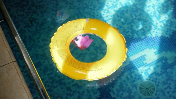 4k video dell'anello gonfiabile giallo e del giocattolo di plastica sulla superficie dell'acqua alla piscina — Video Stock