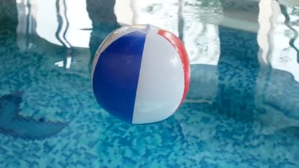 Primer plano 4k metraje de pelota de playa inflable flotando en la piscina cubierta — Vídeos de Stock